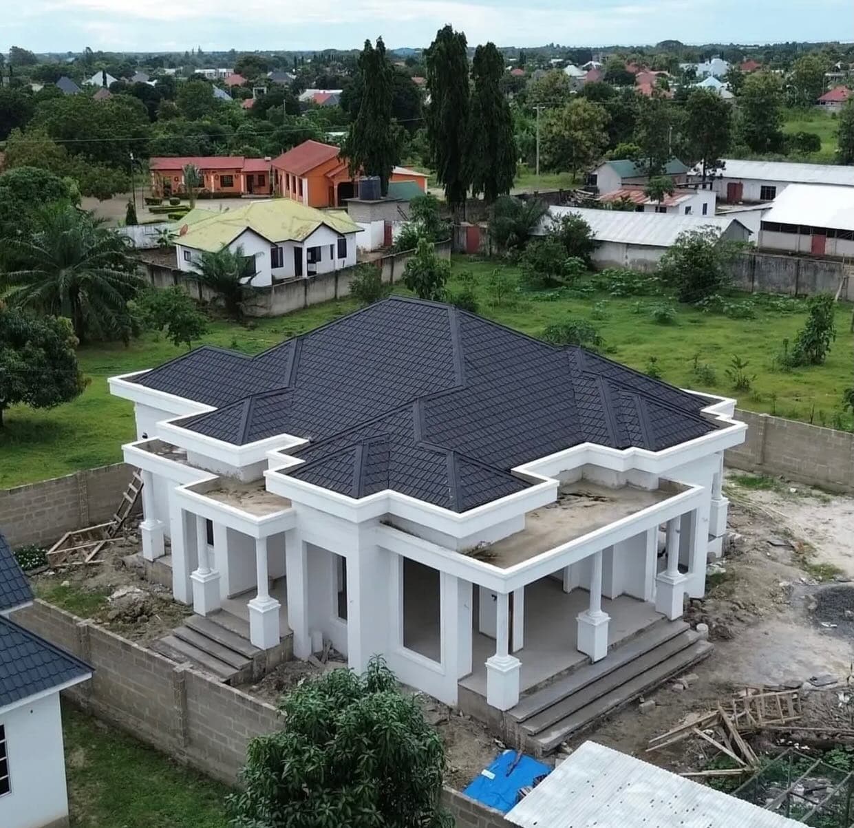 A substantial Kibaha family home with a dark tiled roof and a shaded columned veranda